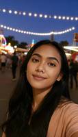Saved edited selfie of a dark-haired woman at an outdoor evening venue with string lights.